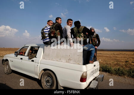 Membri armati del le forze di sicurezza interna noto anche come Asayish Asayis o delle regioni autonome all'interno della lingua curda amministrazione autonoma del nord ed est della Siria a cui spesso viene fatto riferimento come Rojava cavalcare un open-backed pickup truck in Al Hasakah o Hassakeh nella Siria settentrionale Foto Stock