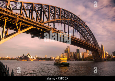 Ferry di Sydney si avvicina alimentazione Milsons Point station wharf Sydney Harbour Bridge e Opera House al tramonto dietro a Sydney in modo nuovo Foto Stock