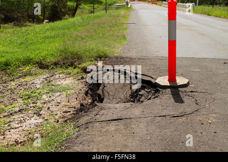 Rotture di asfalto causati dalla pioggia e della subsidenza dovuta a una mancanza di compattazione. Foto Stock