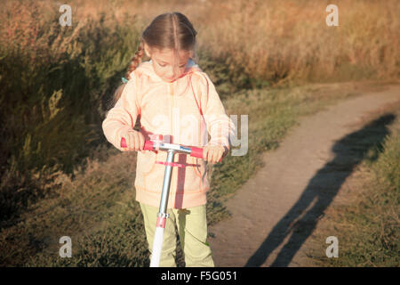 Bella ragazza scooter di guida su strada rurale Foto Stock