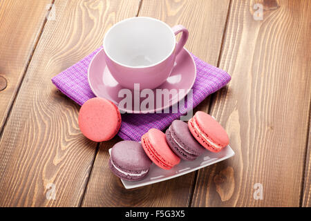 Macaron colorati i cookie e la tazza di caffè sul tavolo in legno sfondo Foto Stock