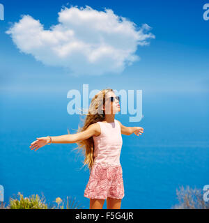 Ragazza bionda scuotendo i capelli in aria a blu mare Mediterraneo turistico in Spagna mani aperte Foto Stock