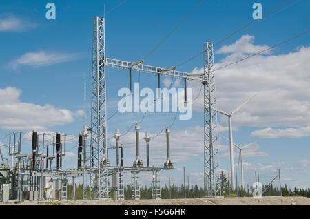 Alcuni mulini a vento e le alte convertitori di tensione e le linee di distribuzione in primo piano immagine dal nord della Svezia. Foto Stock