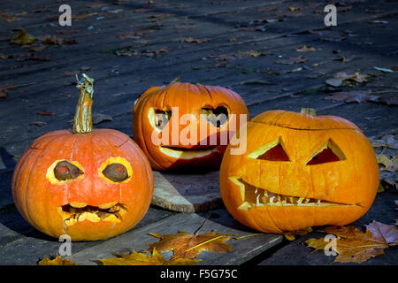 Orrore di Halloween Concetto di vacanza. Tre terribili brutto zucche su un pavimento in legno con foglie di acero nella notte. Foto Stock