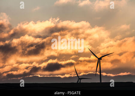 Drammatica nuvoloso golden sky al tramonto con due turbine eoliche stagliano in primo piano Foto Stock
