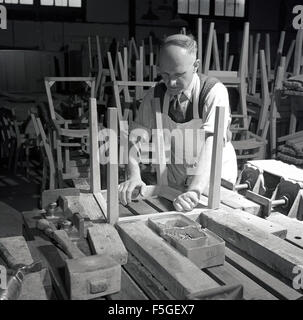 Storico degli anni cinquanta, artigiano o mobili maker o falegname la realizzazione di una sedia in officina. Foto Stock