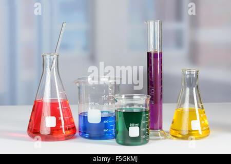 Palloni da laboratorio e bicchieri con liquidi di differenti colori sulla tabella lab Foto Stock