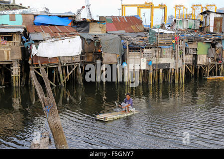 Manila nelle Filippine: residente di un quartiere povero che vivono in capanne su palafitte con legna da ardere su un galleggiante in polistirolo espanso, Tondo township, Manila, Filippine Foto Stock