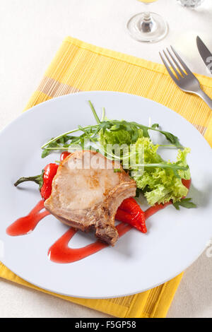 Arrosto di maiale tagliate e pepe rosso guarnita con insalata verde Foto Stock