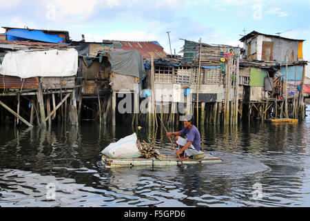 Manila nelle Filippine: residente di un quartiere povero che vivono in capanne su palafitte con legna da ardere su un galleggiante in polistirolo espanso, Tondo township, Manila, Filippine Foto Stock