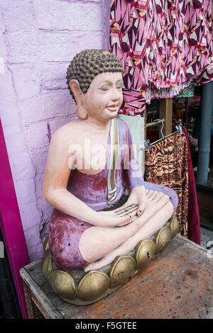 Seduti in meditazione statua del Buddha e la finestra del display lungo Glastonbury High Street,Somerset, Inghilterra. Foto Stock