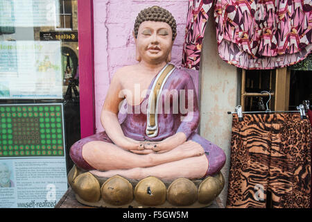 Seduti in meditazione statua del Buddha e la finestra del display lungo Glastonbury High Street,Somerset, Inghilterra. Foto Stock