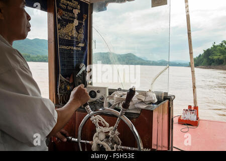 Una barca sul fiume Sterza il capitano di una barca turistica lungo il fiume Mekong vicino a Luang Prabang in Laos Foto Stock