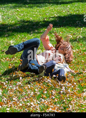 Madre bella riproduzione in erba con la cute giovane figlia, il parco cittadino Foto Stock