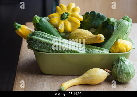 Una varietà di estate squash in un verde rettangolare piatto, su un tavolo Foto Stock