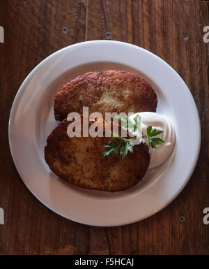 Guardando verso il basso su una piastra con due latkes di patate e panna acida Foto Stock