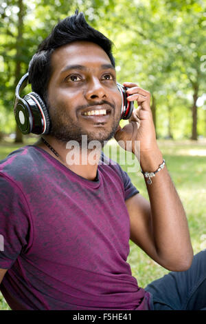 Felice giovane uomo ascoltare musica nel parco Foto Stock