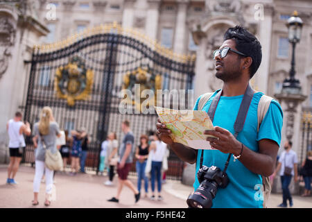 Turismo indiano fuori Buckingham palace in possesso di una mappa e la sua telecamera Foto Stock