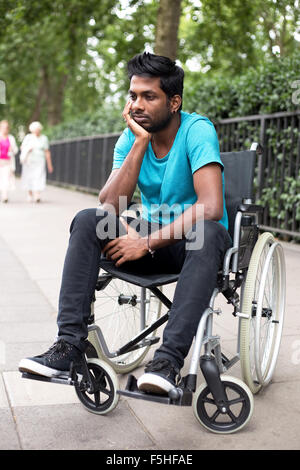 Giovani indiani uomo in sedia a rotelle Foto Stock