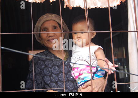 Old Lady tenendo un bambino in una casa in Vietnam Foto Stock