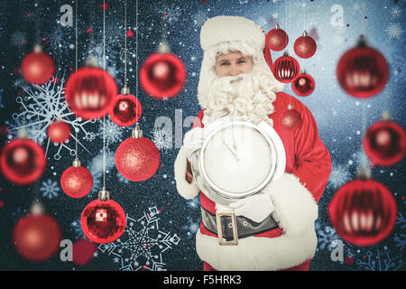 Immagine composita di felice santa tenendo un orologio Foto Stock