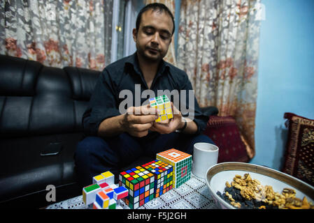 AJ Rais, capo di Kabul Pressistan Media Company, combina il cubo di Rubik in casa sua, Kabul, Afghanistan Foto Stock