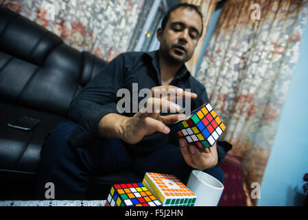 AJ Rais, capo di Kabul Pressistan Media Company, combina il cubo di Rubik in casa sua, Kabul, Afghanistan Foto Stock