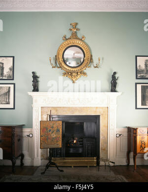 Girandole antico specchio sopra il camino con un antico fuoco-schermo in blu pallido sala da pranzo georgiana Foto Stock