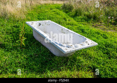 Un vecchio dirty abbandonato bagno bianco in un campo Foto Stock