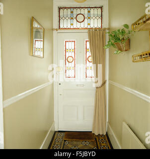 Colorate a pannelli di vetro porta anteriore con tendina acream in Edwardian-style hall Foto Stock