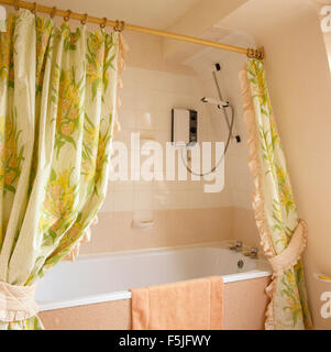 Il giallo tende da doccia su vasca da bagno in piastrelle paese spagnolo  bagno con pavimento in piastrelle di terracotta Foto stock - Alamy