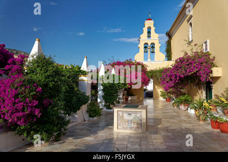 Cortile con fontana e la torre dell orologio e buganvillee, monastero di Panagia Theotokos tis Paleokastritsas o Panagia Theotokos Foto Stock