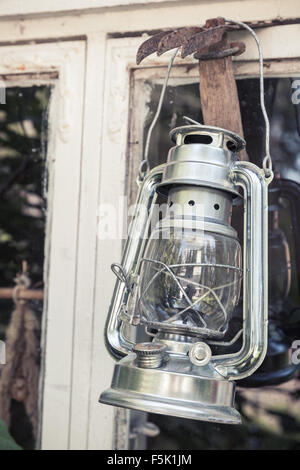 Metallo splendente lampada di kerosene pende su bianco telaio in legno in Finlandia, vintage tonica foto con il vecchio stile di effetto del filtro Foto Stock