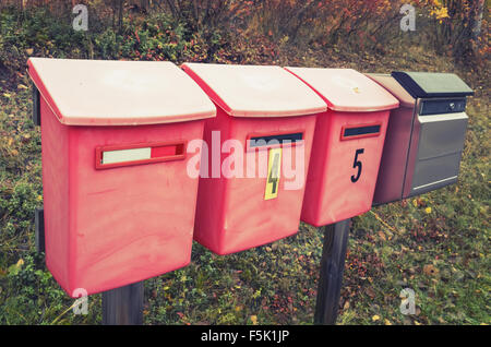 Vecchio rosso caselle di posta su una strada in una fila, vintage la correzione delle tonalità foto effetto filtro Foto Stock