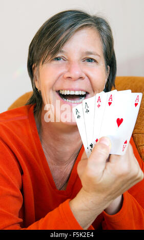 Donna giocando a carte e tenendo premuto 4 assi Foto Stock