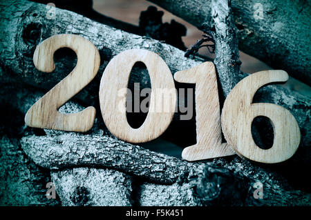 Numeri in legno formando il numero 2016, come il nuovo anno con un mucchio di tronchi in background, con un effetto tonico Foto Stock