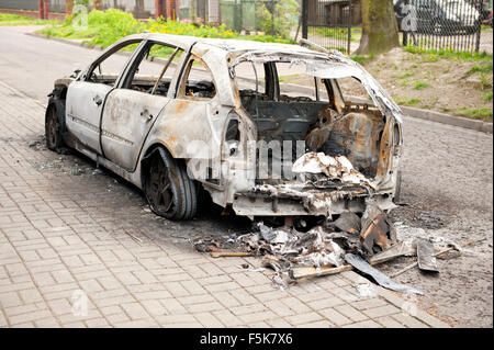 Bruciato auto torna in arson fire, bianco auto rottamata in corrispondenza del pavimento in Polonia, viziati dalla vettura vuota nel fuoco incidente, carbonizzati indesiderata del veicolo Foto Stock