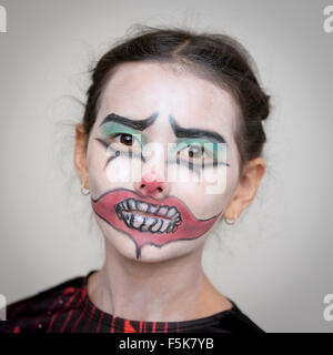 Ritratto di un giovane di 10 anni aveva British / Thai ragazza vestita per Halloween con faccia di clown paint Foto Stock