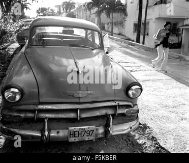 L'Avana, Cuba. 15 feb 2006. Giovane ragazza cubana passeggiate passato uno dei molti cubano Maquinas, aka Yank serbatoi o pre 1960 American Classic Cars per le strade di l'Avana. Il 31 luglio 2006, Castro, dopo essere stati sottoposti a chirurgia intestinale, ha trasferito la propria responsabilità per il vice-presidente e il suo giovane fratello Raoel. Castro una mancata comparizione a suo ottantesimo compleanno ha alimentato i rapporti che ha il terminale di cancro allo stomaco. Funzionari cubani ha affermato che Castro non ha alcuna malattia terminale e finirà per tornare ai suoi doveri pubblici. Cuba è in un 1950's time capsule destinata a cambiare per sempre. Foto Stock