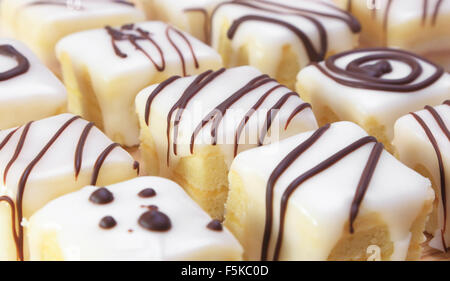 Piazze assortiti di torta al limone ricoperta di glassa e decorata con cioccolato. Foto Stock