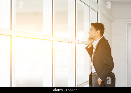 Uomo indiano il controllo sul nuovo ufficio a lasciare e la chiamata sul telefono. Foto Stock