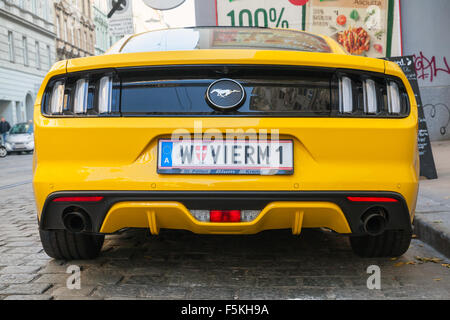 Vienna, Austria - 4 Novembre 2015: Colore giallo brillante Ford Mustang 2015 auto sorge sulla strada di città, vista posteriore Foto Stock