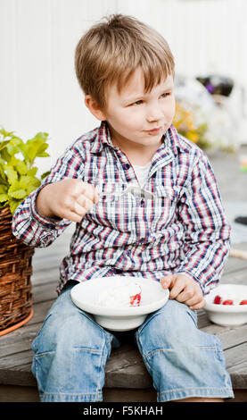 La Svezia Sodermanland, Strangnas, ragazzo (4-5) seduti all'aperto, a mangiare il gelato Foto Stock