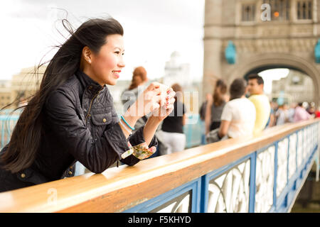 Donna giapponese di scattare una foto con il suo telefono cellulare dal Tower Bridge Foto Stock