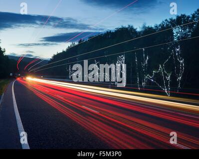 Il traffico autostradale sentieri di luce al tramonto Foto Stock