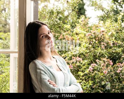 Ritratto di giovane donna appoggiata contro il telaio della porta Foto Stock