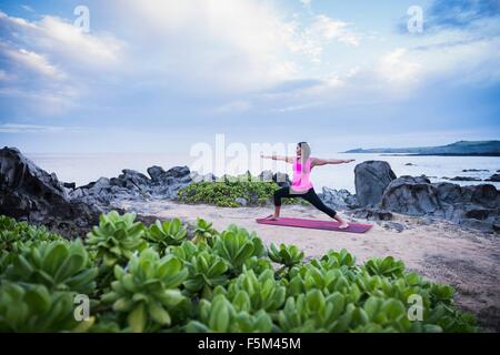 La donna guerriero di praticare lo yoga pone sulla spiaggia, punto Hawea, Maui, Hawaii, STATI UNITI D'AMERICA Foto Stock