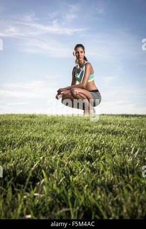 Ritratto di certi athletic giovane donna accovacciata in posizione di parcheggio Foto Stock