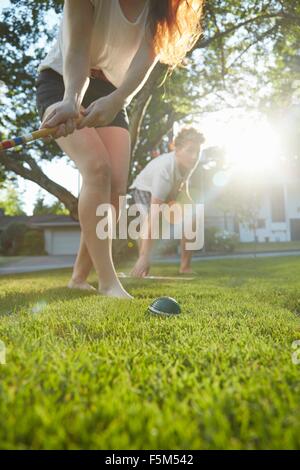 Basso angolo vista della coppia giovane giocando croquet sull'erba Foto Stock