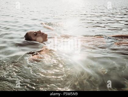 Bella giovane donna galleggianti in mare soleggiato Foto Stock